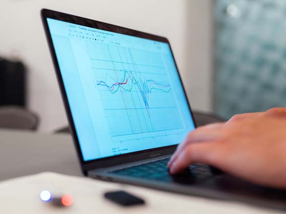 Hands typing on keyboard with graphs on computer screen.