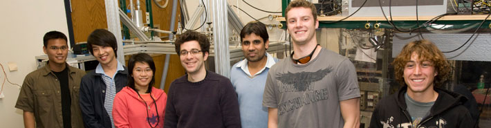 Physics students in a lab with a physics professor.