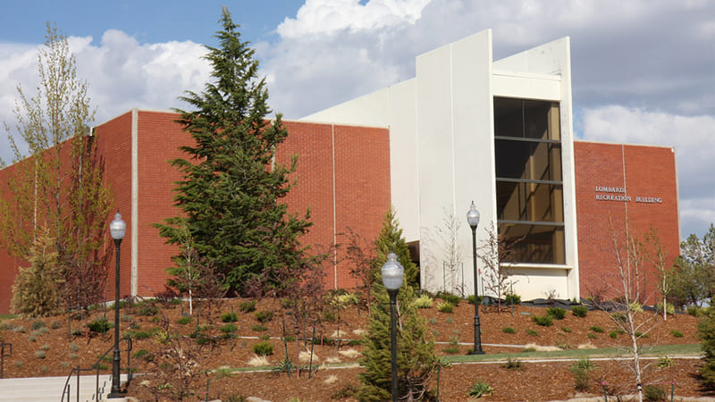 Exterior of 1970s designed Lombardi Recreation with an orange exterior and white window coverings with trees and grass lining the landscaping