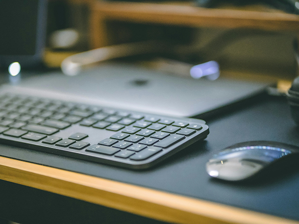 Computer accessories, including a keyboard and a wireless mouse, sit on a desk.