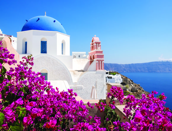 Anatolian architecture surrounded by lush red flora with the sea in the background