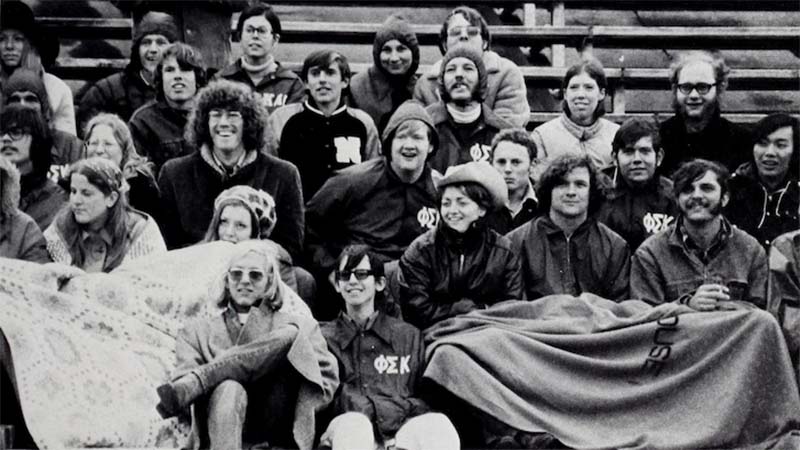 In an archive photo, people sit on bleachers watching a sports event.