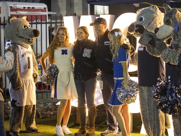 The University President poses for a photo with students and alumni at the tailgate event.