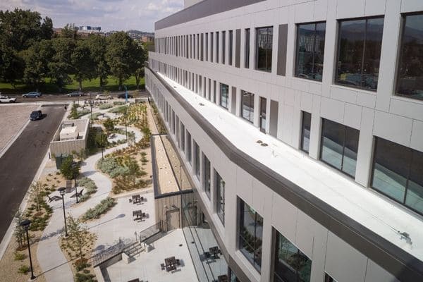 Aerial view of the John Tulloch Building with expansive windows, landscaped grounds, walking paths, and outdoor seating.