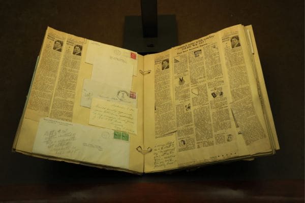 A book with its pages revealing a mix of old newspapers and letters, capturing a glimpse of past stories and communications.