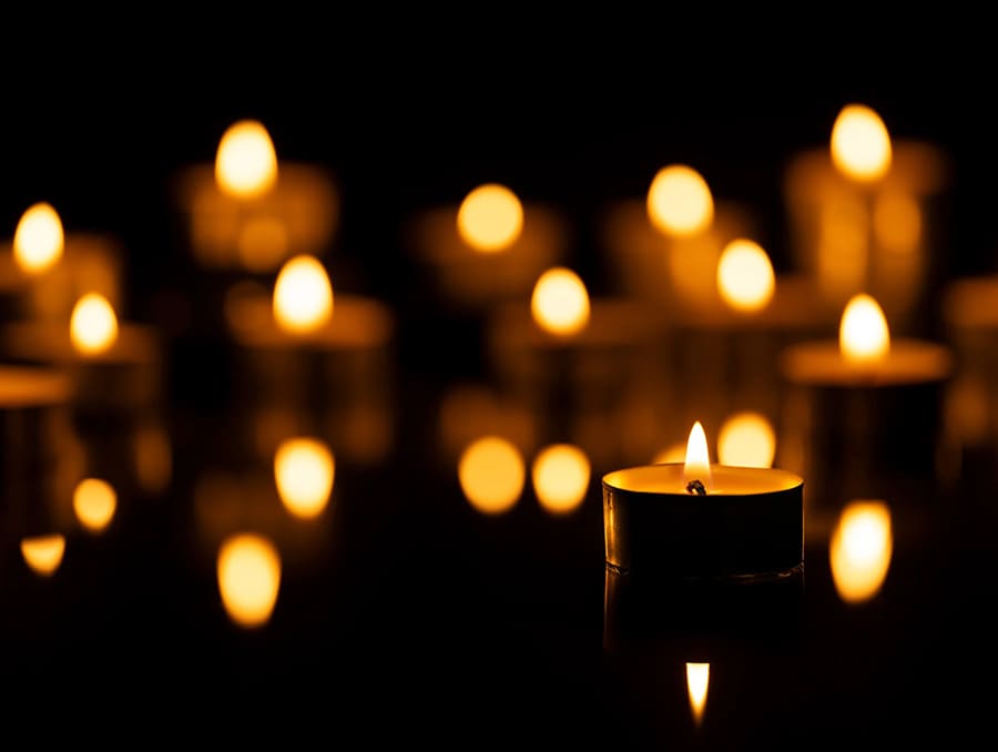 A collection of tealights flicker in a dark room.