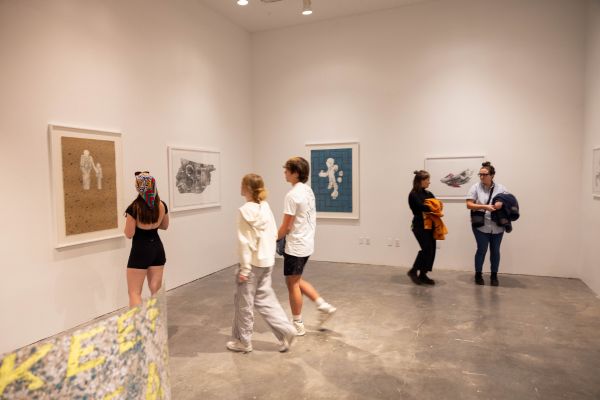 Viewers in a museum walk towards an art piece to admire.