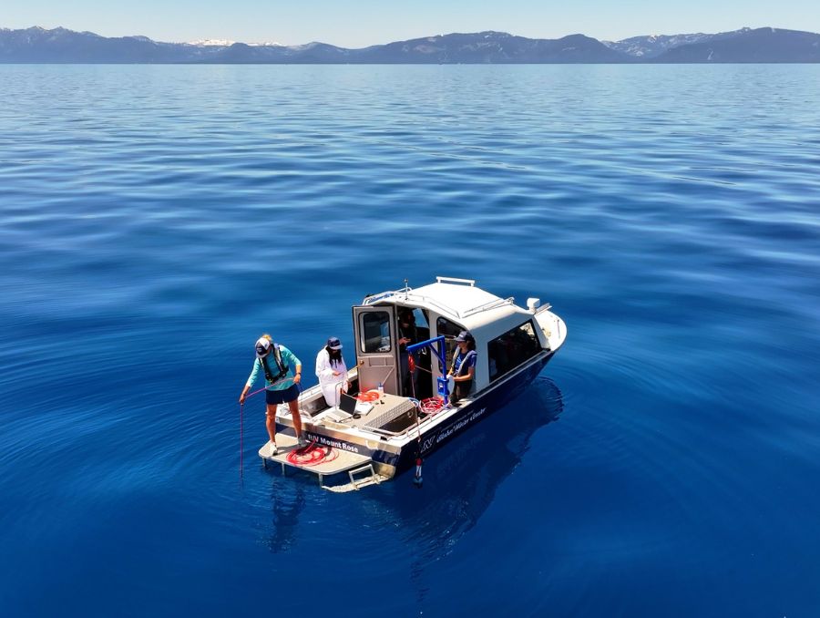 A research team on a boat in Lake Tahoe, surrounded by serene ocean-like scenery.  