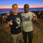 Matt Canepa (left) and Diaz Dixon &lsquo;94 (right) pose with an unidentified individual while making the Wolf Pack hand sign.