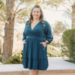 Sara Robbins wears a blue dress and poses for a picture while smiling.