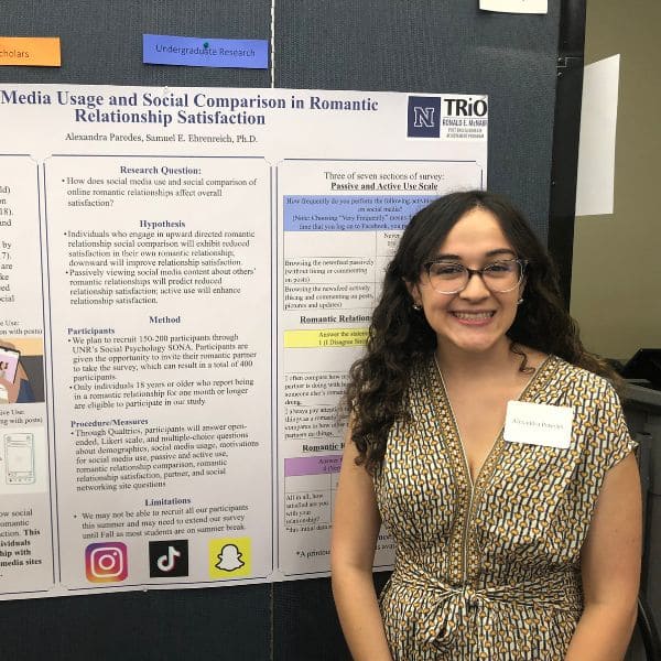 A smiling woman stands beside a research poster titled “Social Media Usage and Social Comparison in Romantic Relationship Satisfaction.” She is wearing glasses and a patterned top.