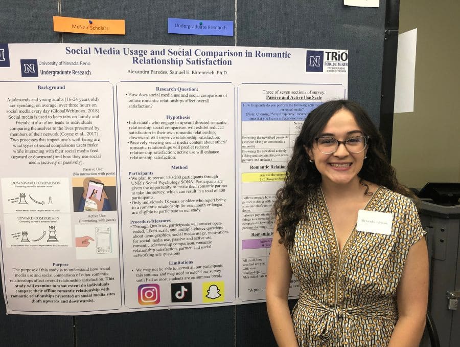 A smiling woman stands beside a research poster titled “Social Media Usage and Social Comparison in Romantic Relationship Satisfaction.” She is wearing glasses and a patterned top.