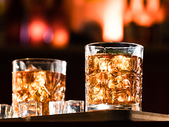 Two glasses of bourbon on a wood table