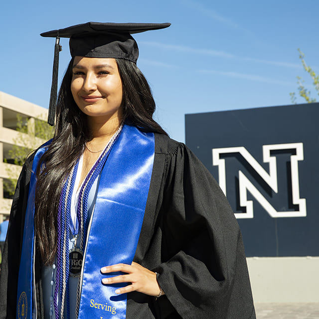 Lizeth Acosta in regalia in front of Nevada N statue