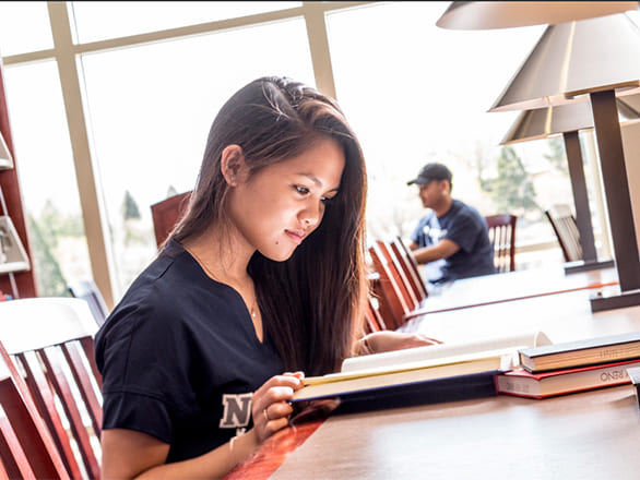 student reading book in the Knowledge Center