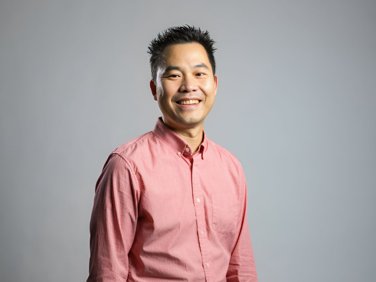 Paul Kwon wears a salmon-colored shirt and stands for a posed photo.