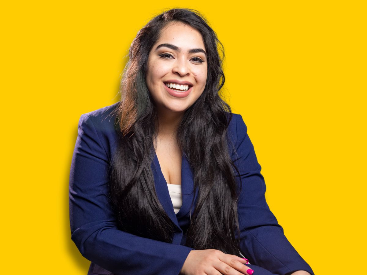 Rosy Chavez-Najera wears a purple blazer and smiles for a photo while seated.