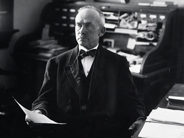 Joseph Stubbs wears a suit and bow tie and sits in his office at the University of Nevada, Reno