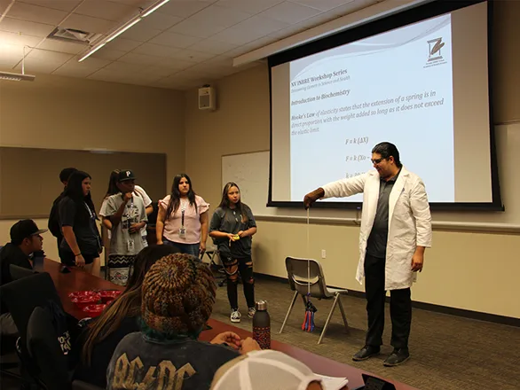 A group of students watch an instructor conduct a science experiment during the 2023 Native Students LEAD program.