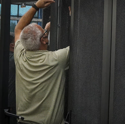 Man working in a technology cabinet.