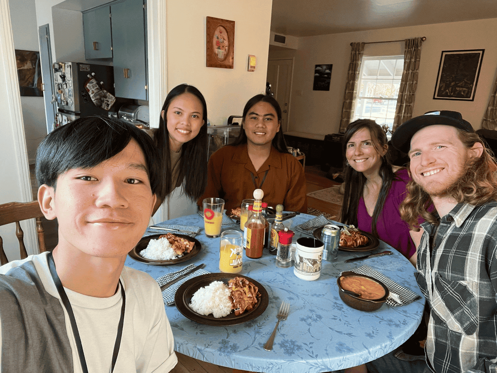 Five people sitting down for dinner together in an American home.