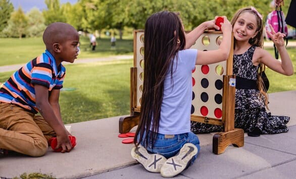 Kids playing extra large Connect Four in a park.
