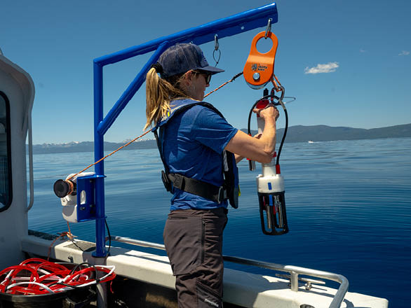 A researcher prepares a plastics data collection instrument on a boat in Lake Tahoe