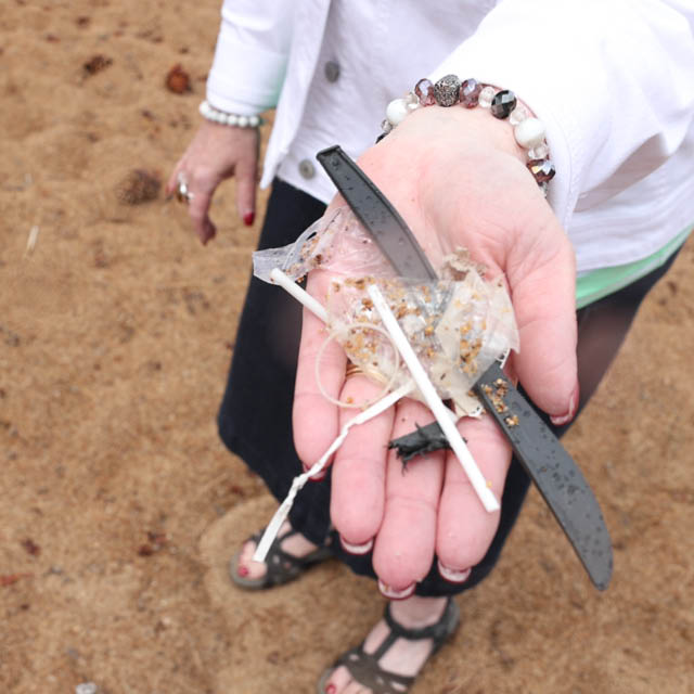A hand holding plastics with a Lake Tahoe beach in the background.