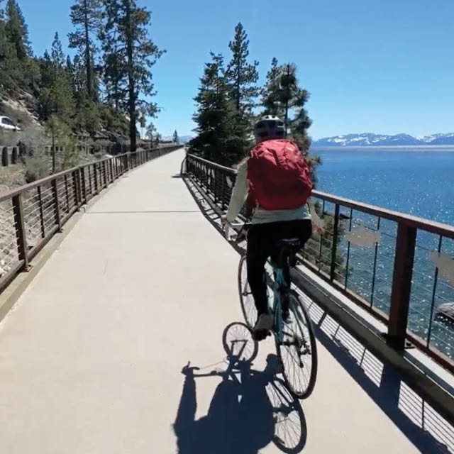 A biker on a bike path near the edge of the lake.