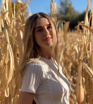 Savannah is in a corn field, with dried corn stalks behind her.