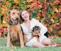 Simone is with a dog and there is fall foliage behind her