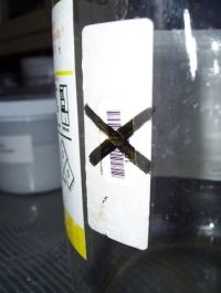 Bottle with thick black inked in X over the UNR barcode.