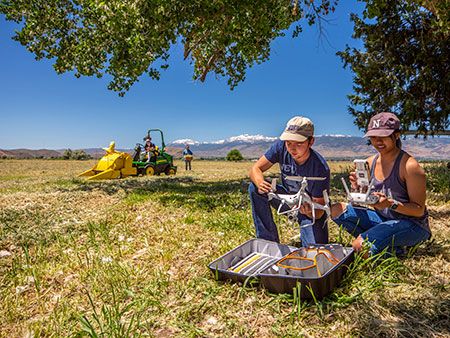University researchers working with a drone near an agricultural area.