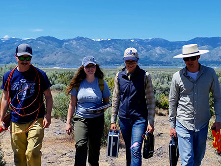 Field research team carrying equipment.