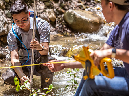 Field research team gathering data in a stream.