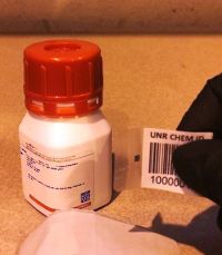 Close-up of a gloved hand sticking the RFID barcode label to the bottle