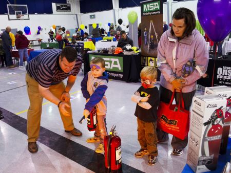 An EH&S member giving a fire extinguisher demo to children at an event on campus