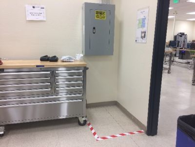 A breaker box with a safety line taped to the floor in front of it