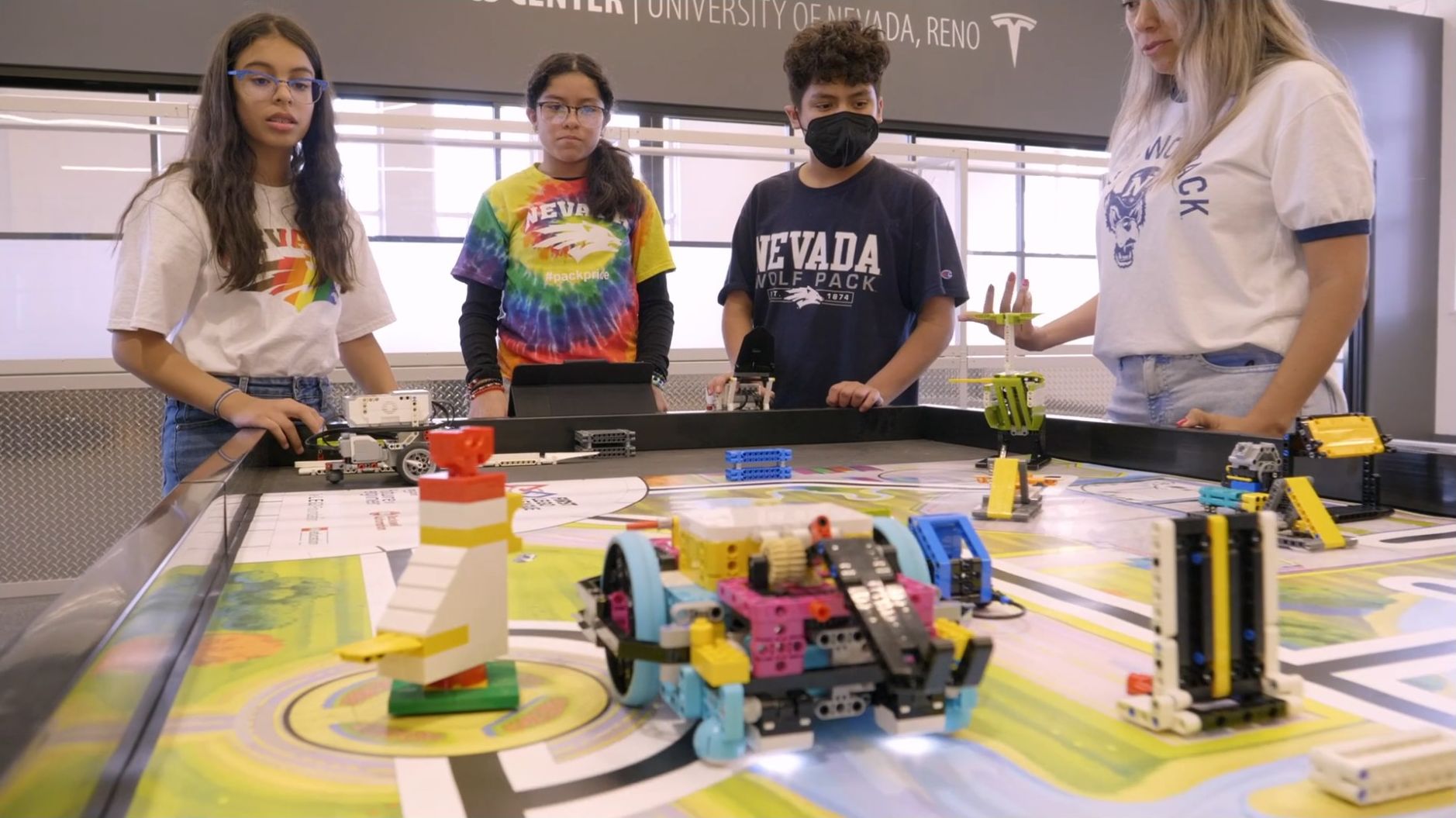 Students and mentor practicing with robots on a competition board in the K-12 Robotics Center