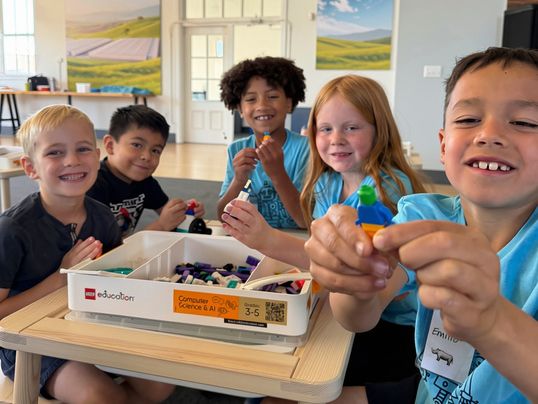 A group of children show off their LEGO creations while participating in the FIRST LEGO League Explore program.