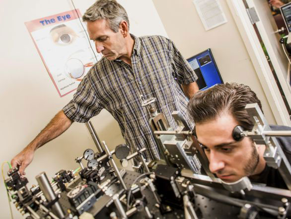 A faculty researcher conducting a neuroscience study related to the eyes on a participant