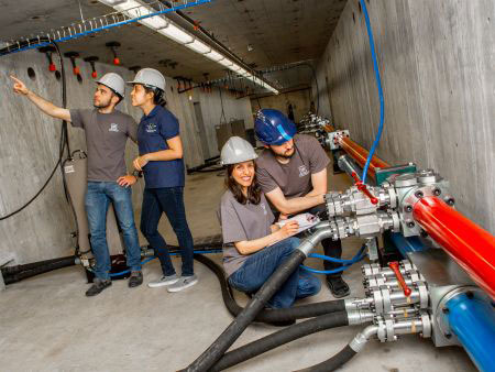 Four people wearing hard hats and working in a concrete tunnel in the Earthquake Engineering Laboratory