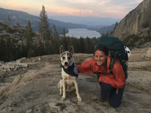 Sarah Bisbing, Ph.D, on a field work backpacking trip and posing with her dog, Dawkins