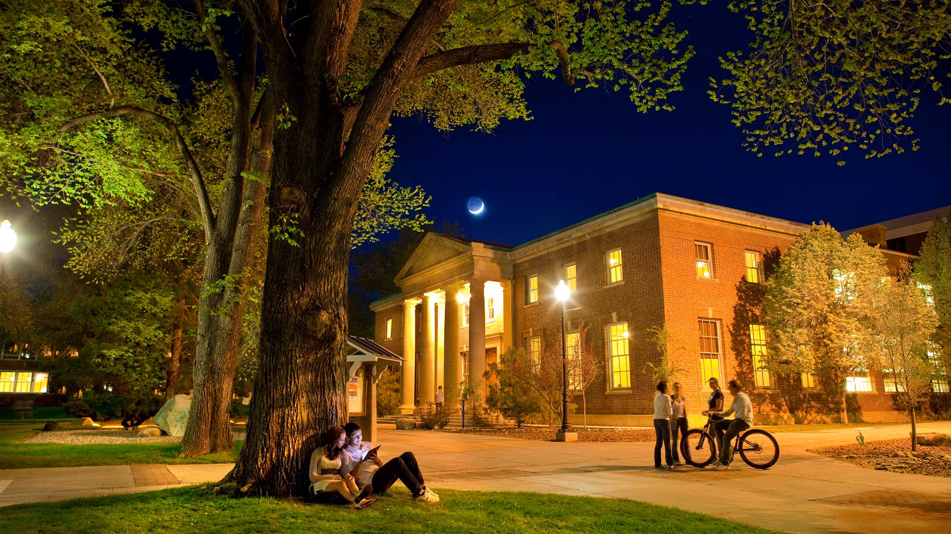 Mackay Mines building at night, with students studying on the quad outside the building