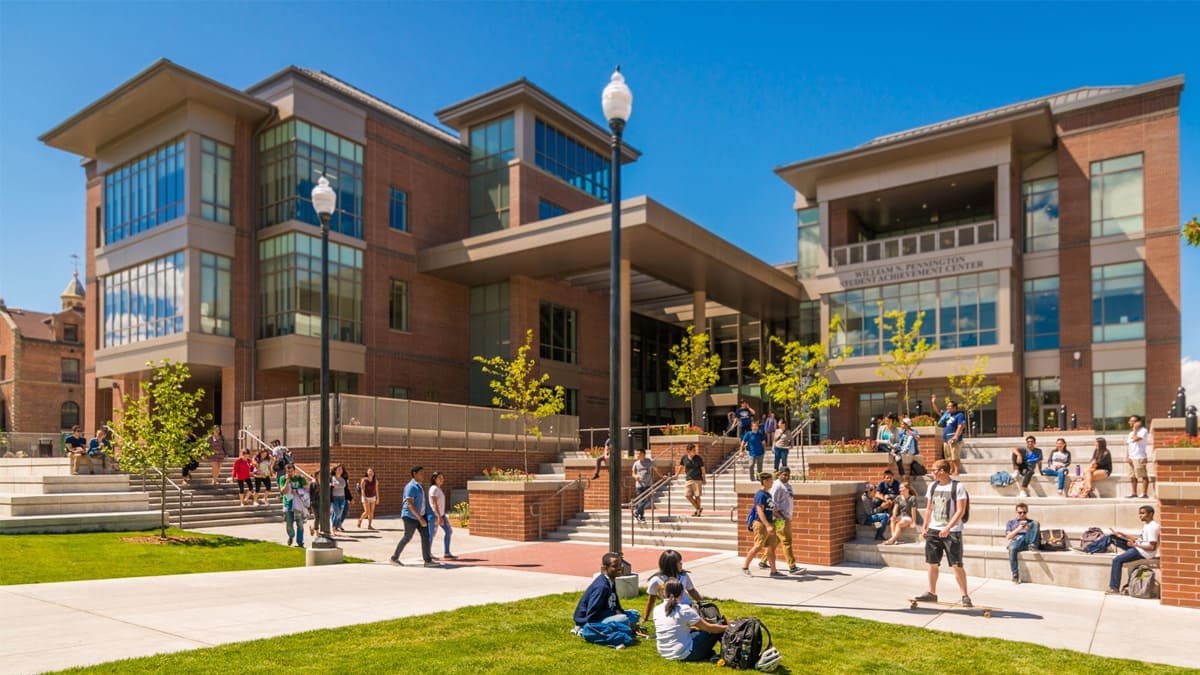 The Pennington Student Achievement Center on a sunny day, with students walking by and socializing on the steps and grass