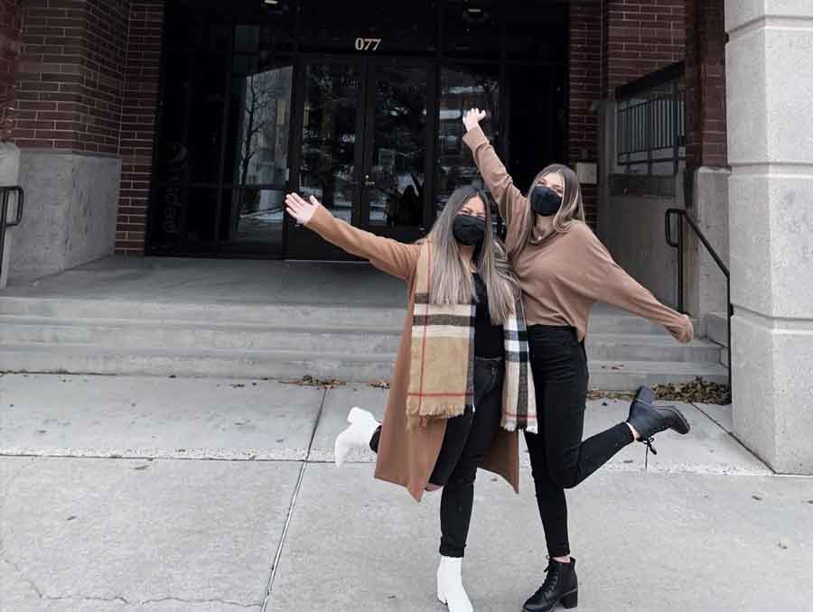 Kyla Kwan and a friend pose in front of a building on campus