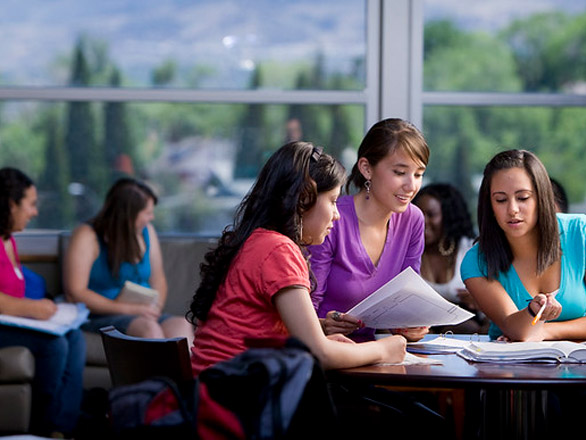 Groups of students study at different tables in the Joe Crowley Student Union with large windows in the background showing trees and mountains in the distance.
