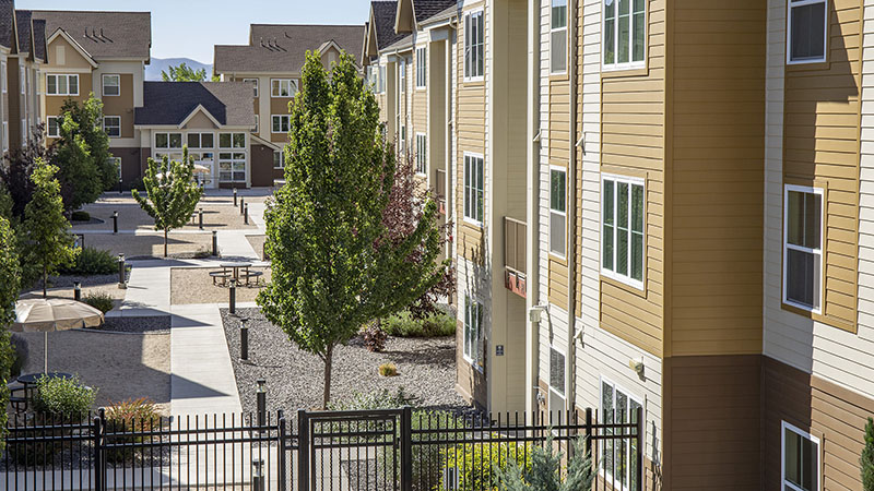 Exterior of Ponderosa Village: a sidewalk winds through a xeriscaped apartment complex.