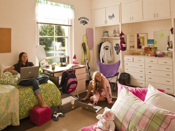 A group of students seated inside Manzanita Hall, engaged in conversation and study. The interior features modern design elements with neutral tones, large windows.