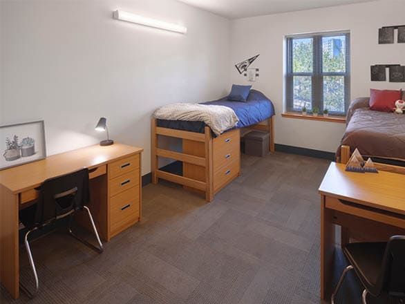 A double bedroom in Nevada LLC Hall with two beds, two desks, and a large window. Minimalist decor and neutral tones create a welcoming atmosphere.